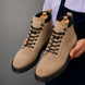 Man holding a pair of Melodiapelle Meilbourne Combat Boots in sand beige suede, close-up