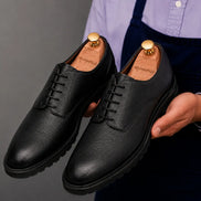 Man holding a pair of Melodiapelle Meridian Derby Shoes in black leather, close-up