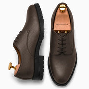 Dark brown leather plain-toe Derby, three-quarter angle showing heel and sole detailing