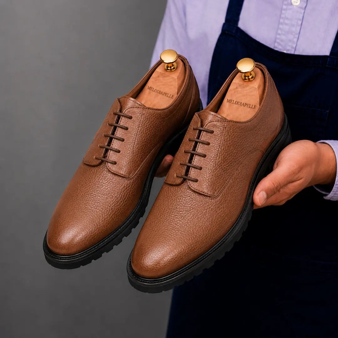 Man holding a pair of Melodiapelle Meridian Derby Shoes in tan leather, close-up
