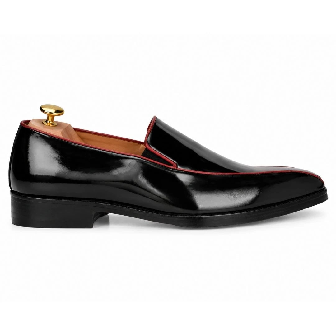 Side profile of the Merlot Dress Loafer in nero black leather with red piping on white background