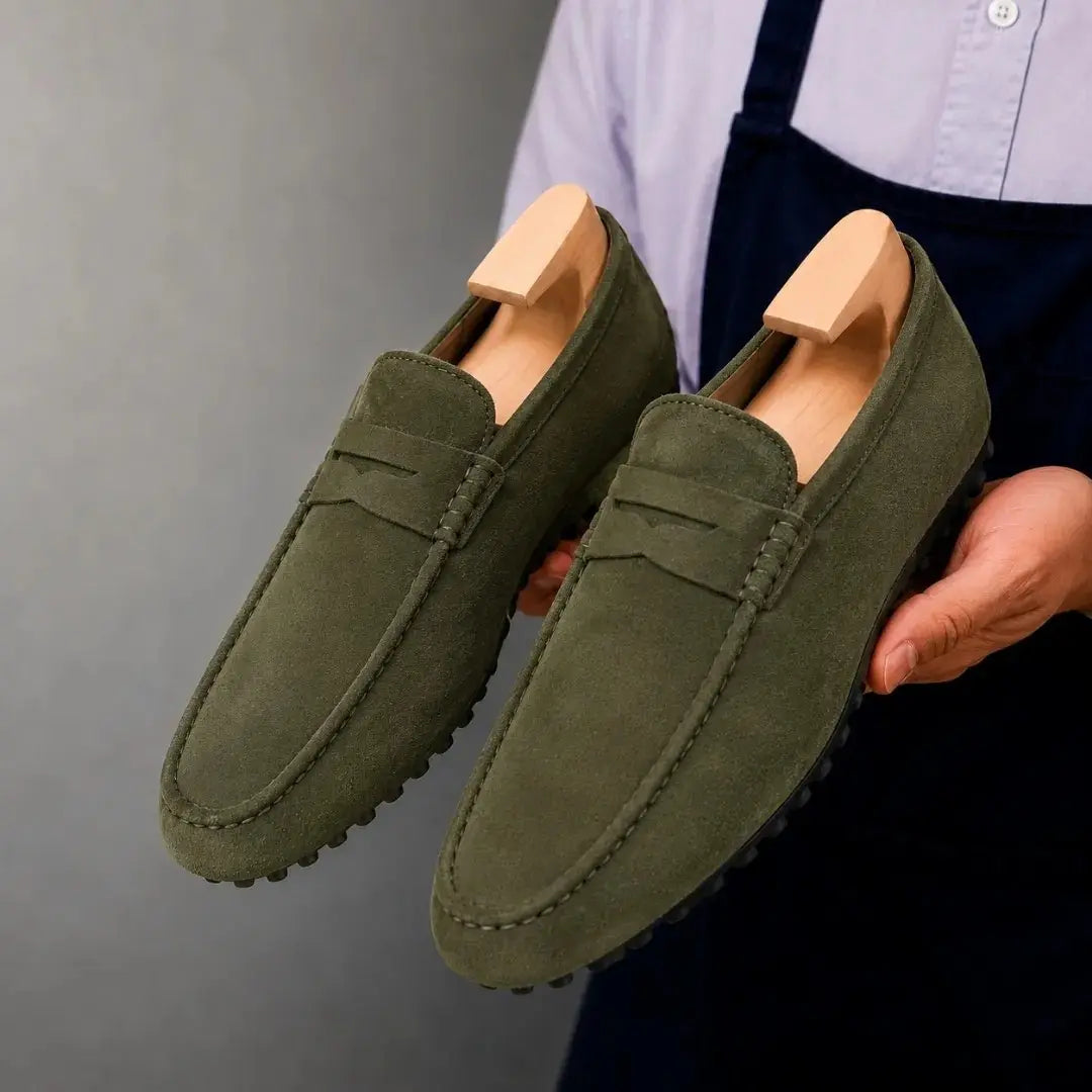 Man holding a pair of Melodiapelle Merrifield Loafers in olive green suede, close-up