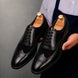 Man holding a pair of Melodiapelle Meta Semi-Brogue Oxford shoes in nero black leather, close-up