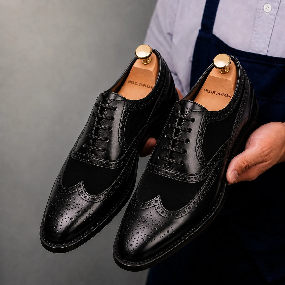 Man holding a pair of Melodiapelle Meta Semi-Brogue Oxford shoes in nero black leather, close-up