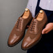 Man holding a pair of Melodiapelle Meta Semi-Brogue Oxford shoes in tan leather, close-up