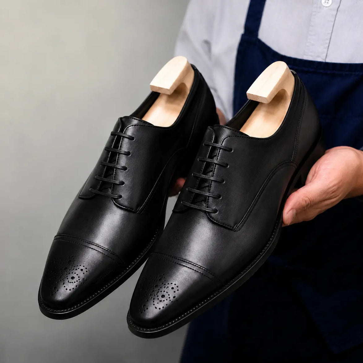 Man holding a pair of Melodiapelle Meta Wholecut Oxford shoes in black leather, close-up