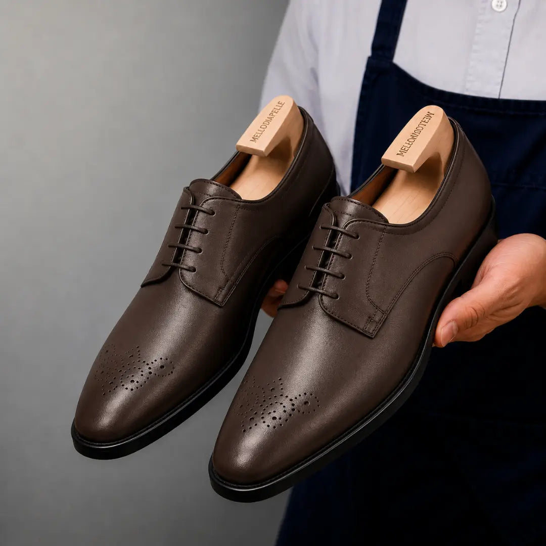 Man holding a pair of Melodiapelle Meta Wholecut Oxford shoes in brown leather, close-up