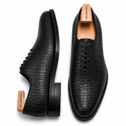 Black croc-embossed leather wholecut Oxford, three-quarter angle showing heel and texture detailing