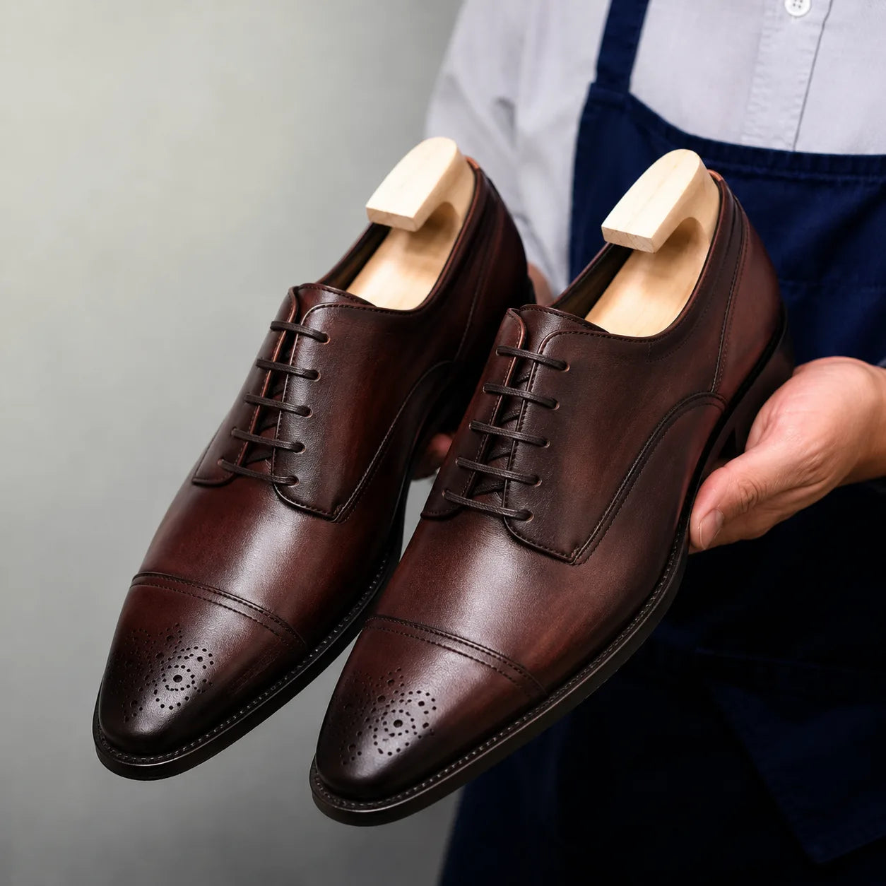 Man holding a pair of Melodiapelle Meta Wholecut Oxford shoes in oxblood bordeaux leather, close-up
