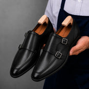 Man holding a pair of Melodiapelle Mexico Double Monk Strap shoes in black leather, close-up