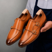 Man holding a pair of Melodiapelle Mexico Double Monk Strap shoes in honey tan burnished leather, close-up