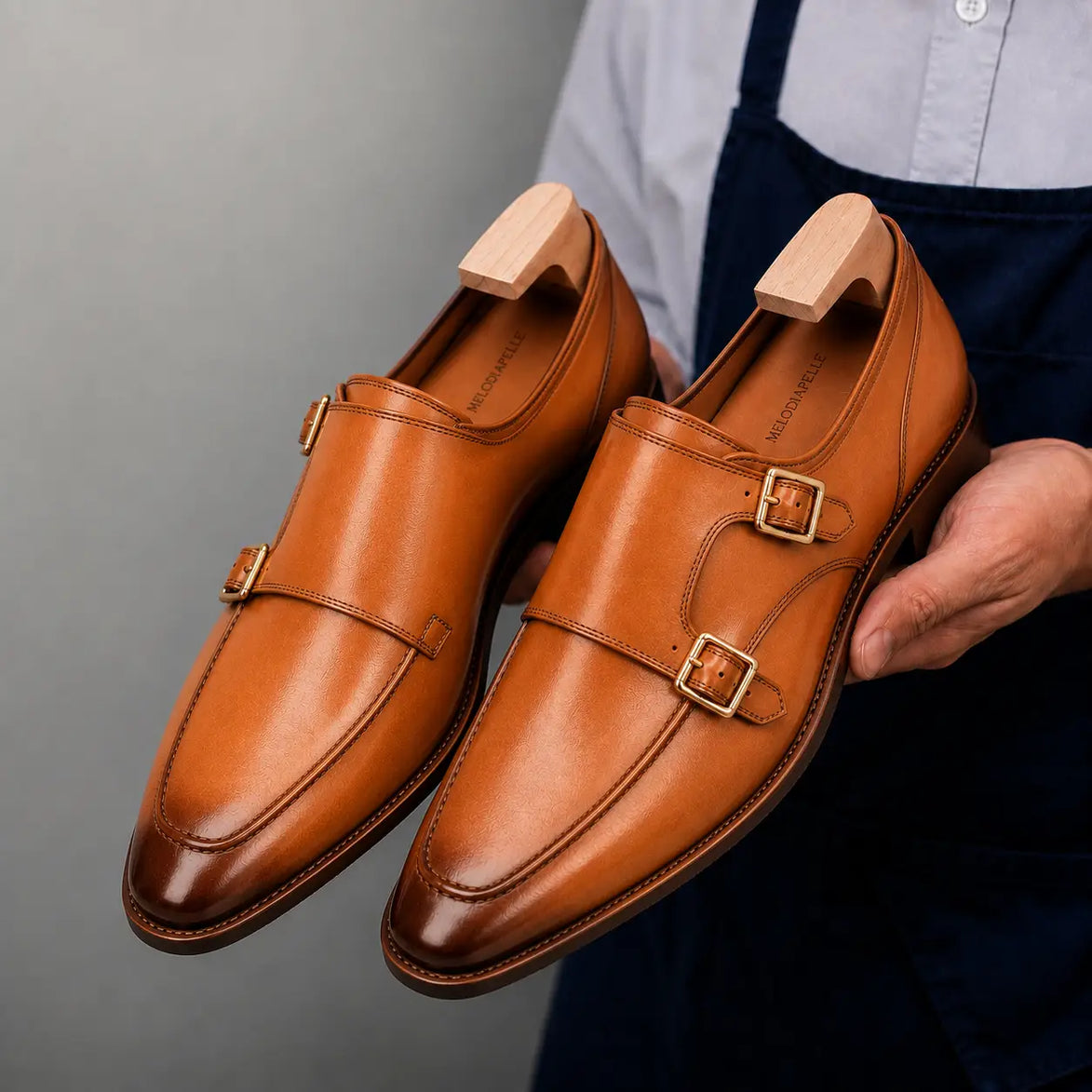Man holding a pair of Melodiapelle Mexico Double Monk Strap shoes in honey tan burnished leather, close-up