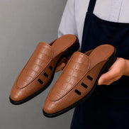 Man holding a pair of Melodiapelle Miami Mule shoes in tan leather, close-up