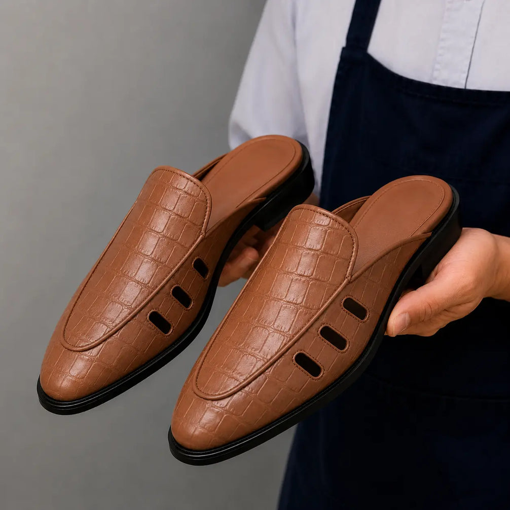 Man holding a pair of Melodiapelle Miami Mule shoes in tan leather, close-up