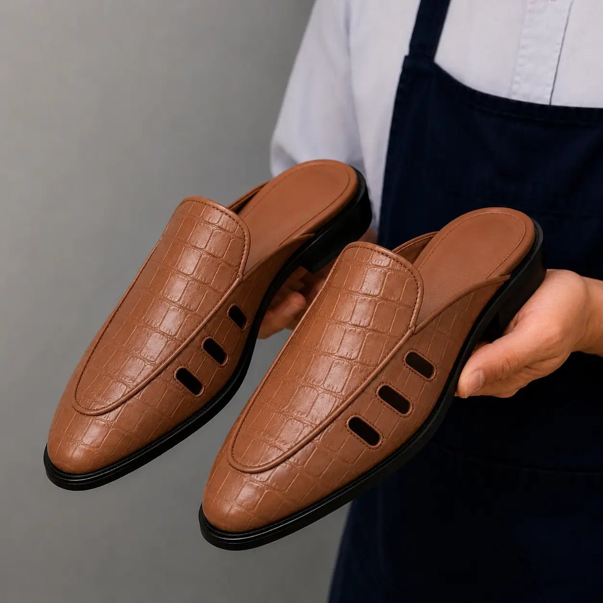 Man holding a pair of Melodiapelle Miami Mule shoes in tan leather, close-up