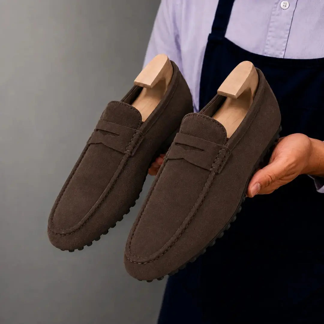 Dark brown suede penny loafer, three-quarter angle showing sole detailing
