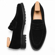 Black suede penny loafer, three-quarter angle showing heel and lug-sole detailing