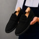 Man holding a pair of Melodiapelle Midland Loafer shoes in black suede, close-up