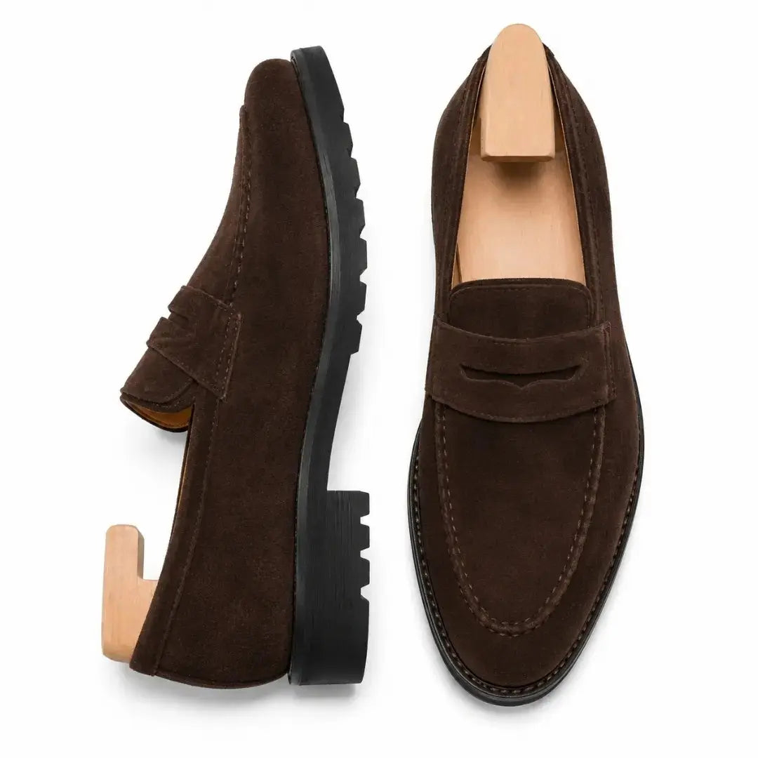 Dark brown suede penny loafer, three-quarter angle showing heel and lug-sole detailing