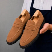 Man holding a pair of Melodiapelle Midland Loafer shoes in rust tan suede, close-up