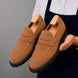 Man holding a pair of Melodiapelle Midland Loafer shoes in rust tan suede, close-up