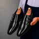 Man holding a pair of Melodiapelle Milan Triple Monk Strap Loafer shoes in nero black leather, close-up