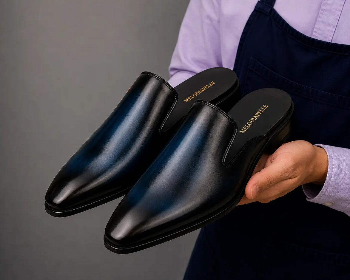 Man holding a pair of Melodiapelle Millburn Mules in black leather, close-up