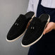 Man holding a pair of Melodiapelle Millo Mule shoes in black suede, close-up