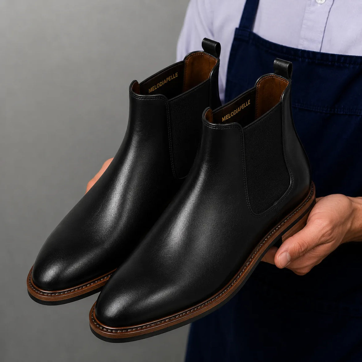 Man holding a pair of Melodiapelle Mirage Chelsea Boots in nero black leather, close-up