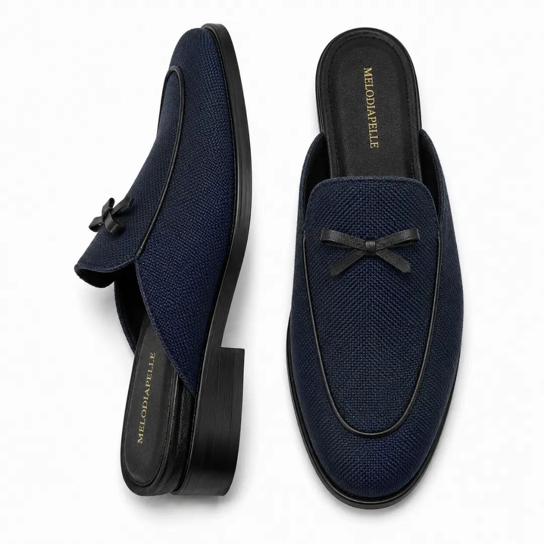 Navy textured suede mule with bow trim, three-quarter angle showing heel and bow detailing