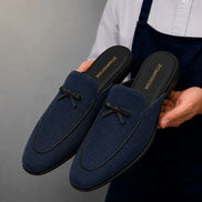 Man holding a pair of Melodiapelle Missoni Mule shoes in navy textured suede, close-up