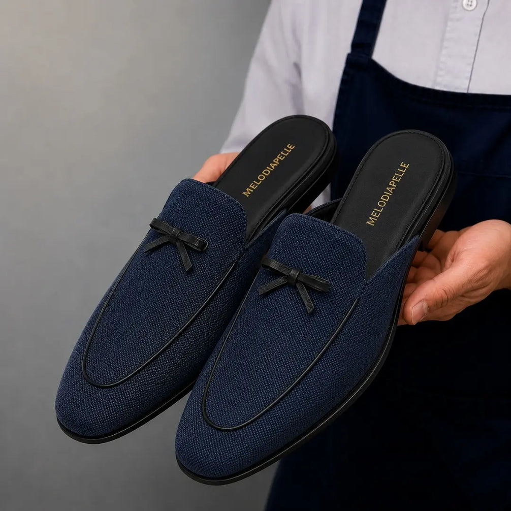 Man holding a pair of Melodiapelle Missoni Mule shoes in navy textured suede, close-up