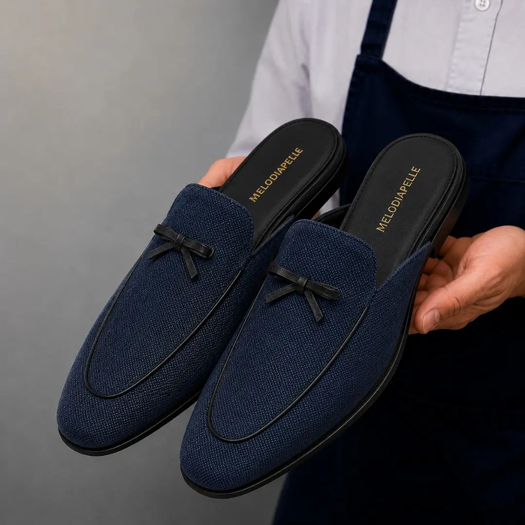 Man holding a pair of Melodiapelle Missoni Mule shoes in navy textured suede, close-up