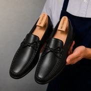 Man holding a pair of Melodiapelle Missouri Loafers in black leather, close-up