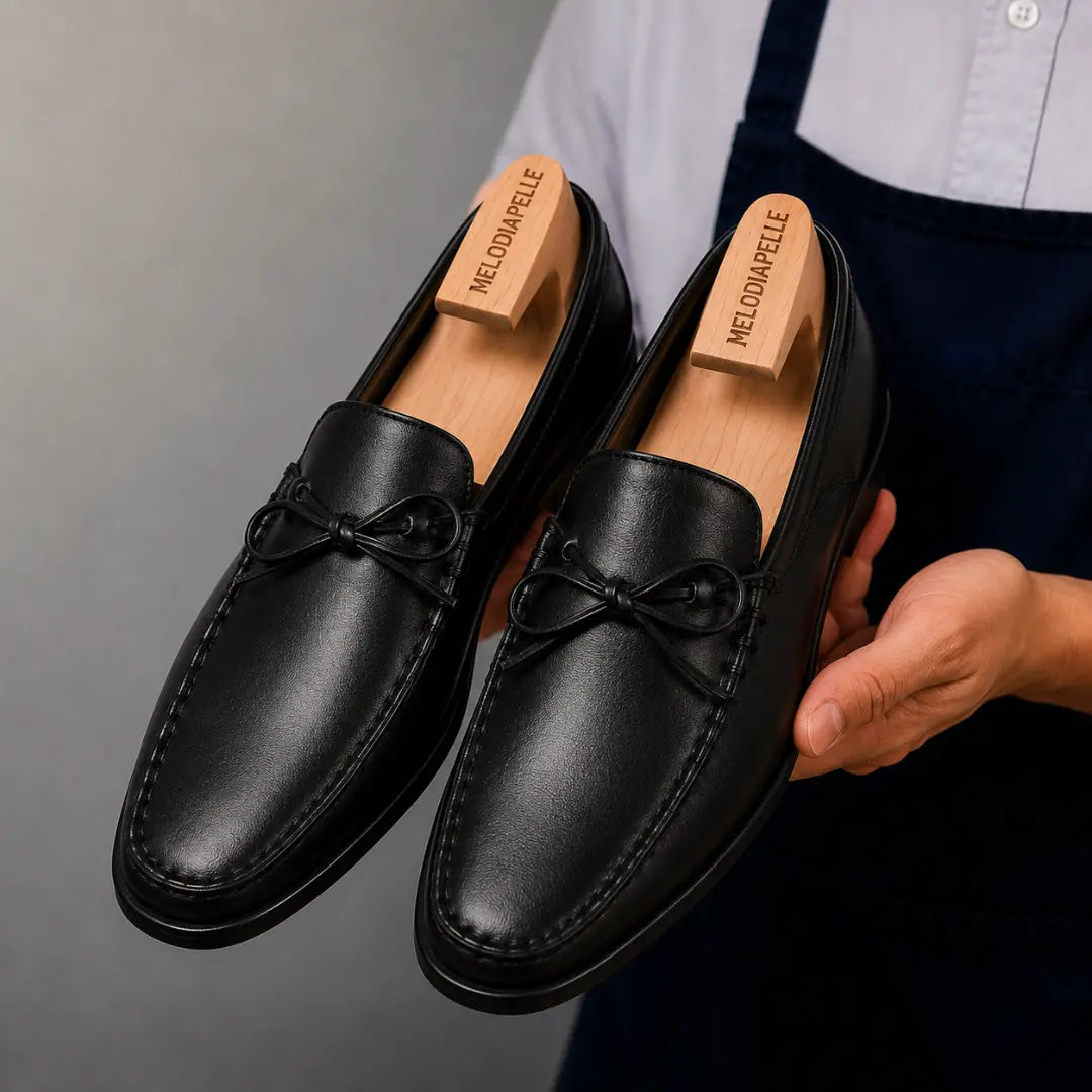 Man holding a pair of Melodiapelle Missouri Loafers in black leather, close-up