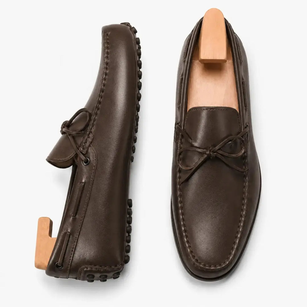 Dark brown leather driving loafer with bow lace, three-quarter angle showing sole detailing