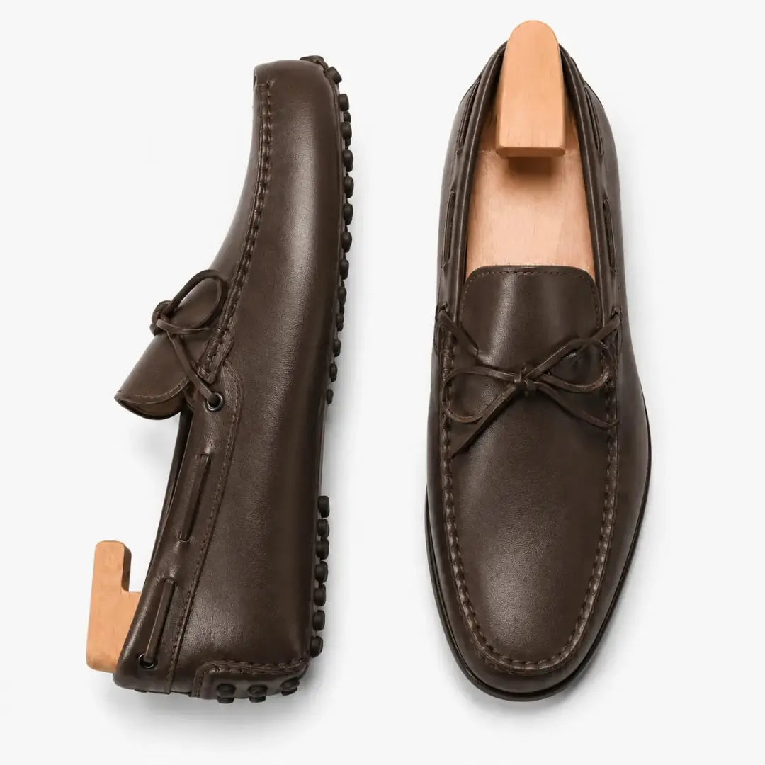 Dark brown leather driving loafer with bow lace, three-quarter angle showing sole detailing
