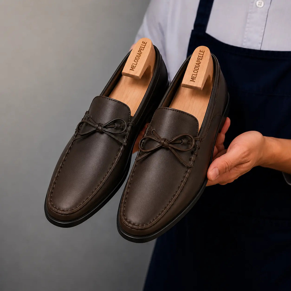 Man holding a pair of Melodiapelle Missouri Loafers in dark brown leather, close-up