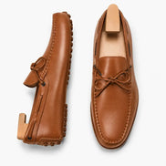 Tan leather driving loafer with bow lace, three-quarter angle showing sole detailing