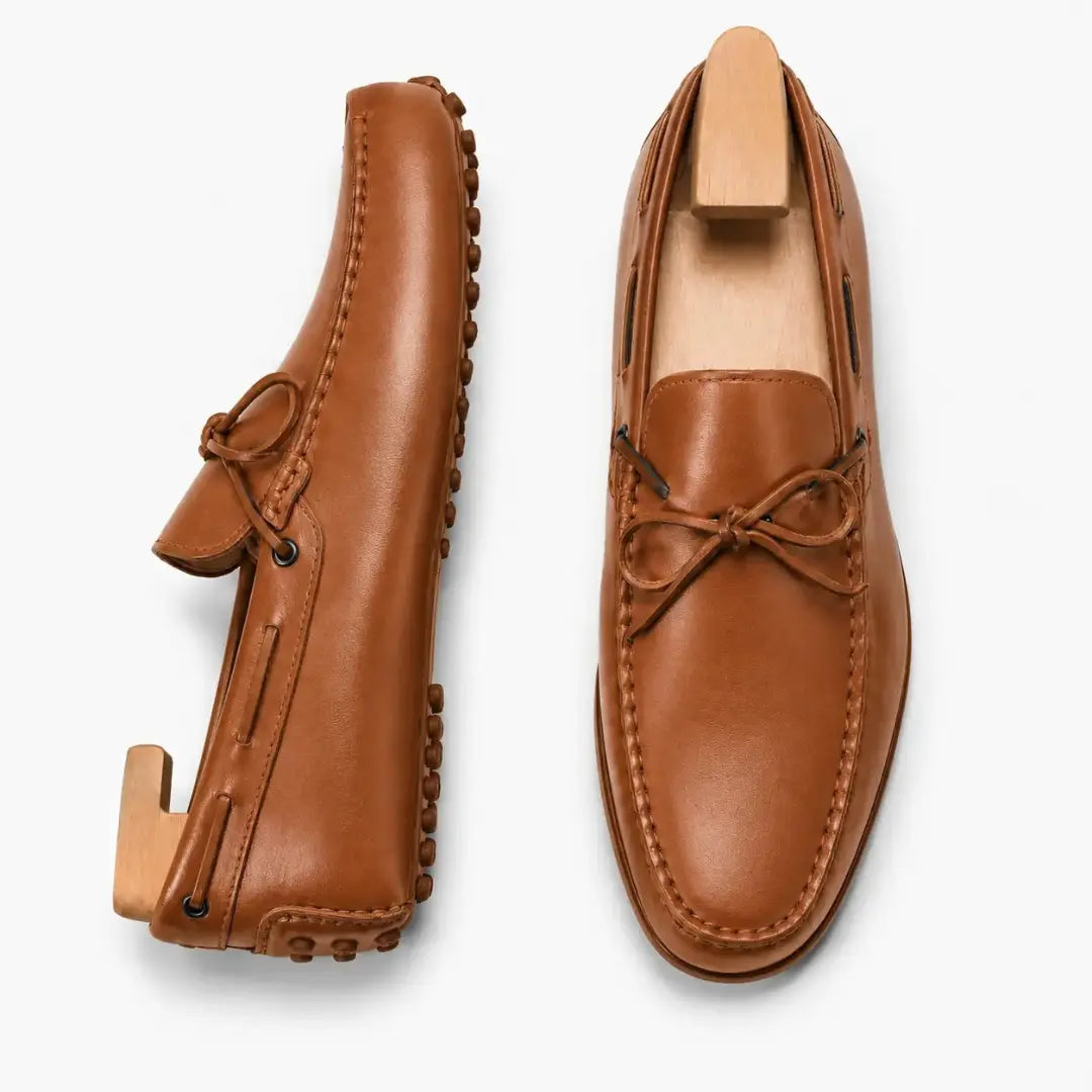Tan leather driving loafer with bow lace, three-quarter angle showing sole detailing