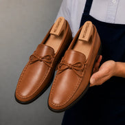 Man holding a pair of Melodiapelle Missouri Loafers in tan leather, close-up