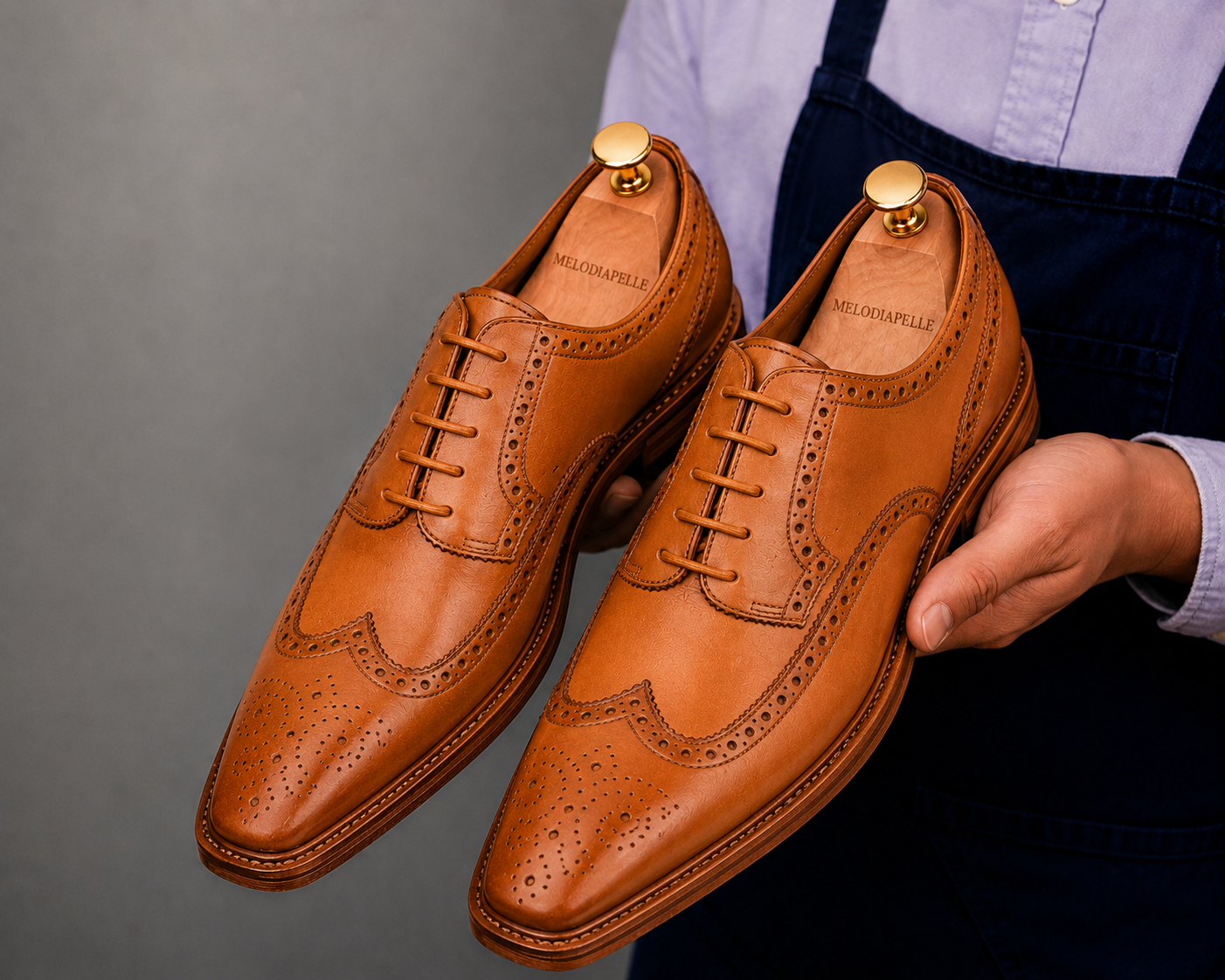 Man holding a pair of Melodiapelle Missourie Longwing Brogue Derby shoes in natural tan leather, close-up