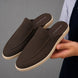 Man holding a pair of Melodiapelle Mole Mule shoes in dark brown suede, close-up