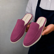 Man holding a pair of Melodiapelle Mole Mule shoes in magenta pink suede, close-up