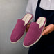 Man holding a pair of Melodiapelle Mole Mule shoes in magenta pink suede, close-up