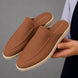 Man holding a pair of Melodiapelle Mole Mule shoes in tan rust suede, close-up