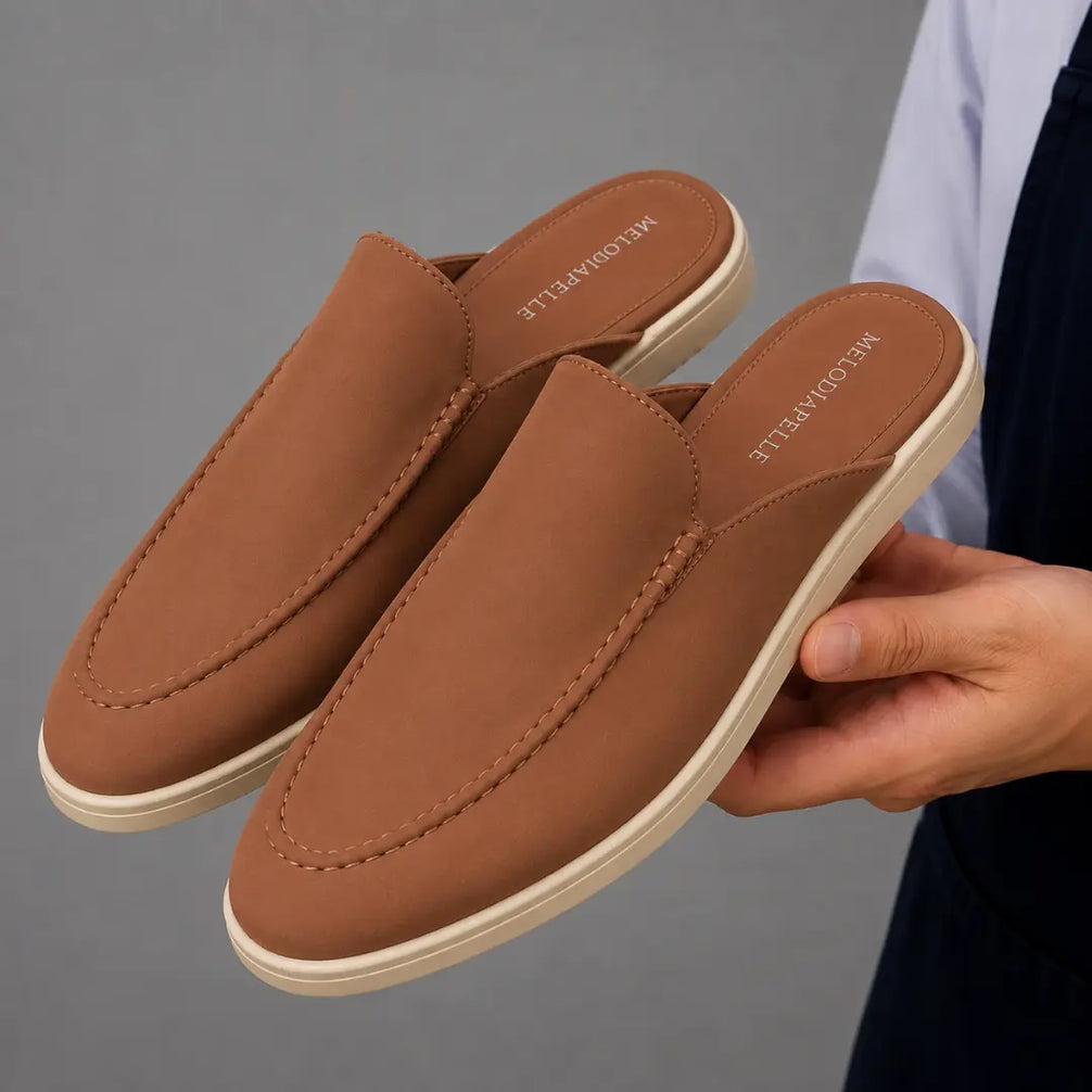Man holding a pair of Melodiapelle Mole Mule shoes in tan rust suede, close-up