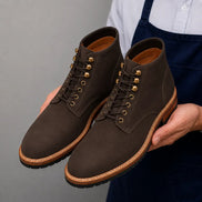 Man holding a pair of Melodiapelle Montblanc Heritage Lace-Up Boots in brown leather, close-up