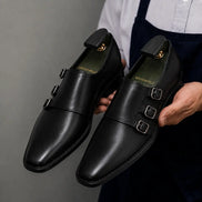 Man holding a pair of Melodiapelle Montecito Double Monk Strap shoes in black leather, close-up