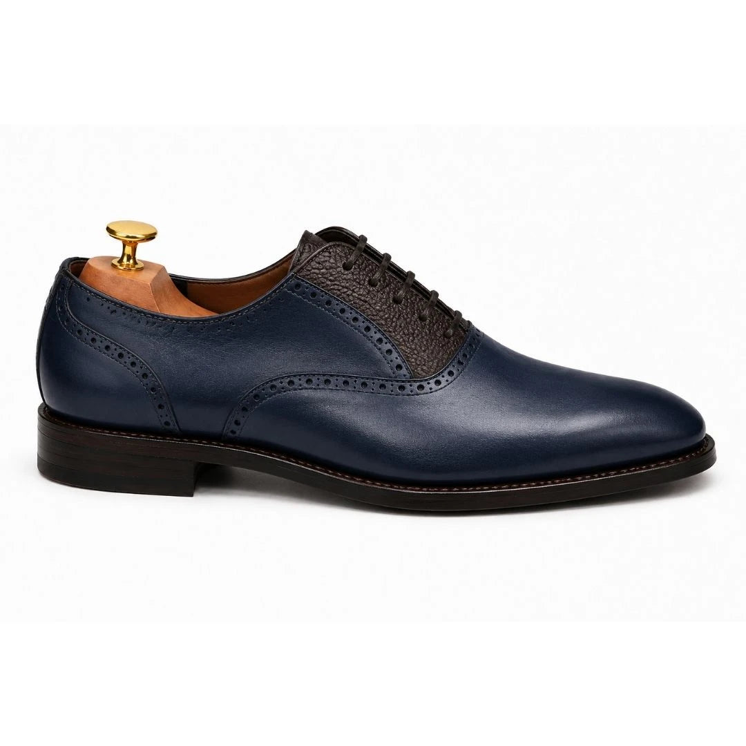 Side profile of the Montserrat Two-Tone Saddle Oxford in navy and dark brown leather on white background